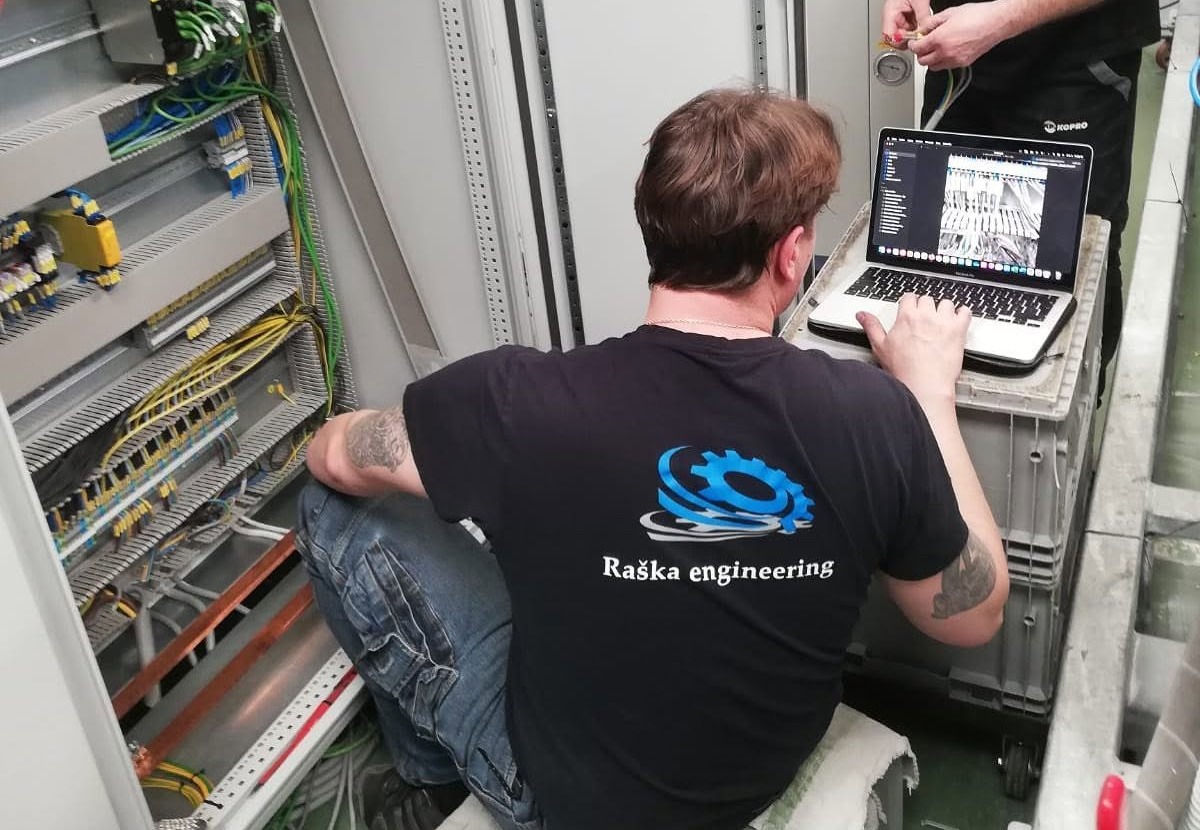 Technik Raška engineering při práci na rozvaděči s notebookem